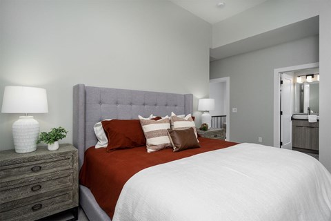 A bedroom with a large bed and a grey headboard.