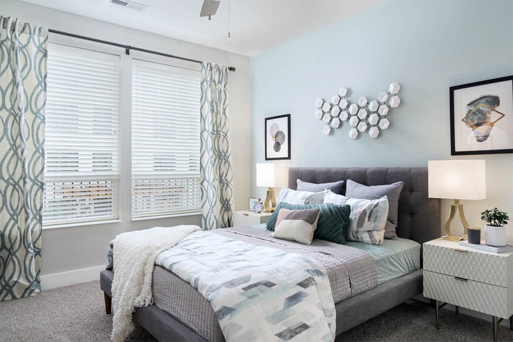 A bedroom with a bed, nightstand, and wall art.