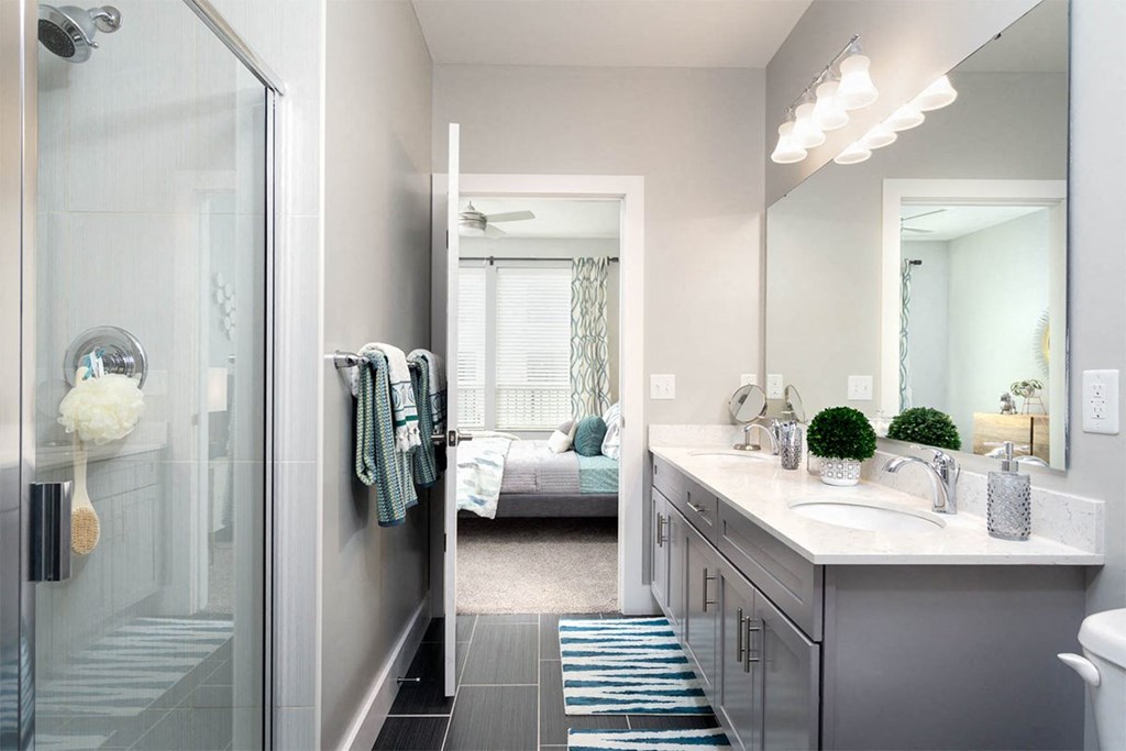 A bathroom with a white sink, a mirror, and a glass shower door.
