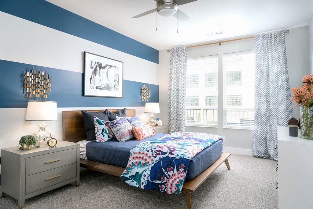 A bedroom with a bed, nightstand, and a ceiling fan.