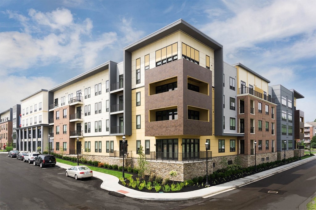 A row of modern apartment buildings with cars parked in front.