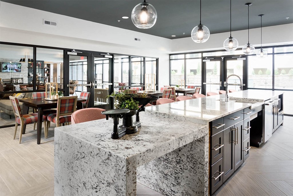 A kitchen with a marble island and pendant lights.