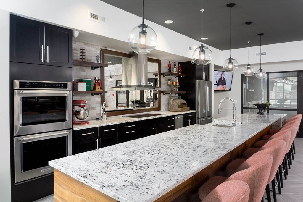 A modern kitchen with a marble countertop and black cabinets.