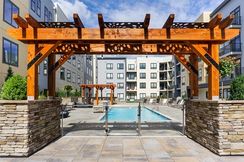 A wooden pergola over a pool in a residential area.