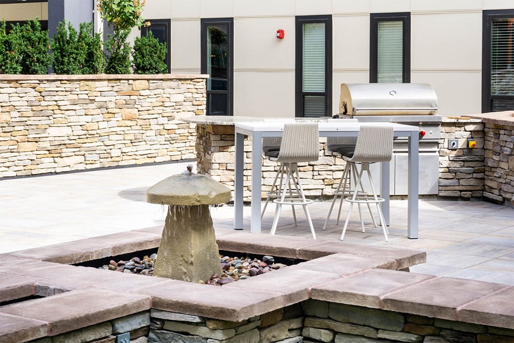 A stone fountain is in the middle of a patio.
