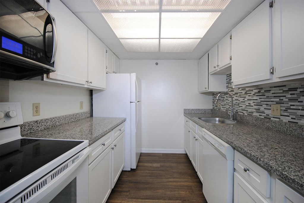 A kitchen with white cabinets and granite countertops.