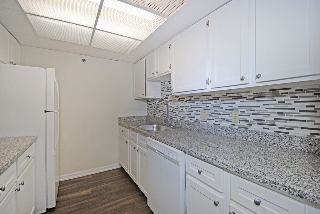 A kitchen with white cabinets and a granite countertop.