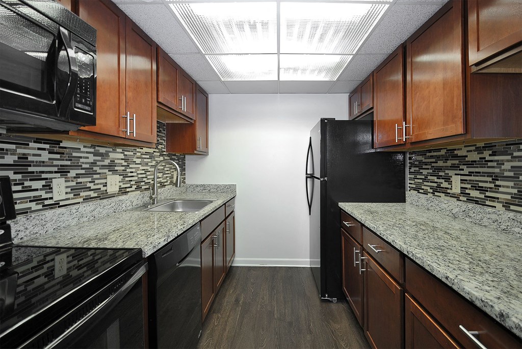 A kitchen with black appliances and wooden cabinets.