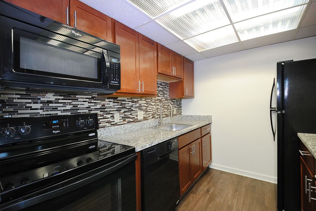 A kitchen with black appliances and wooden cabinets.