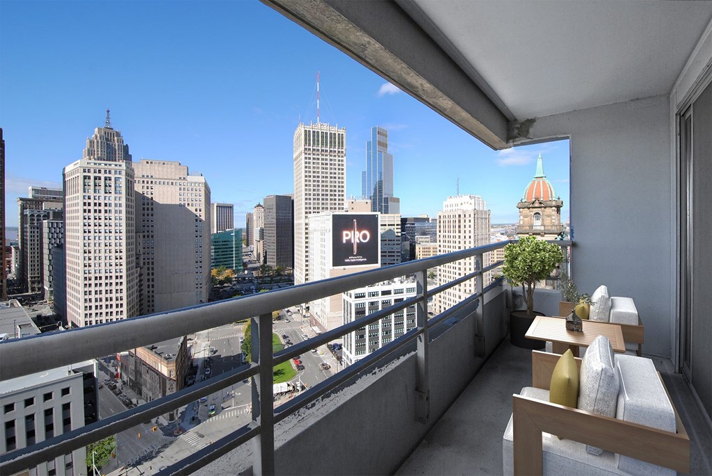 A balcony with a table and chairs overlooking a cityscape.