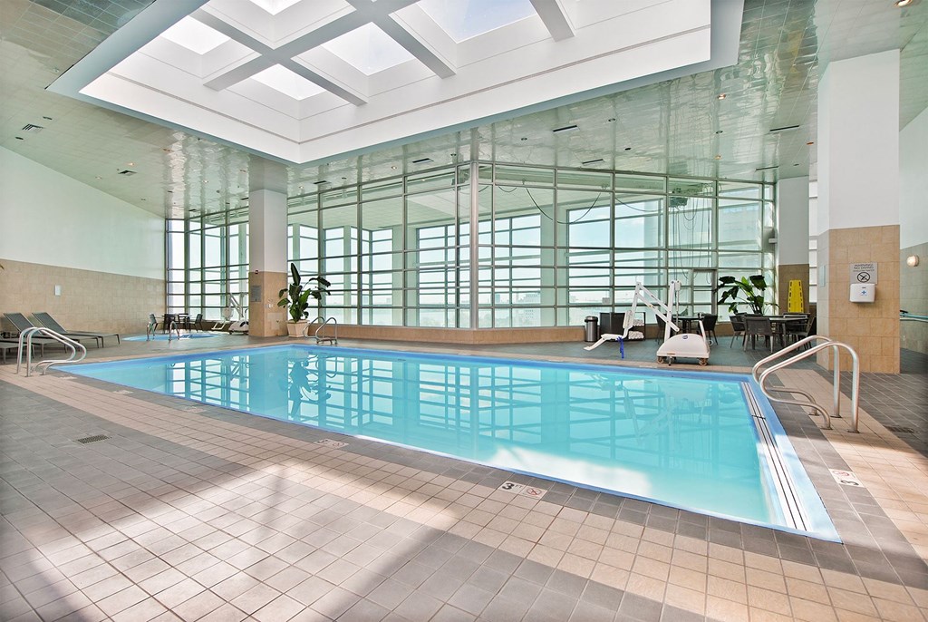 A large indoor swimming pool with sunlight streaming in through the windows.