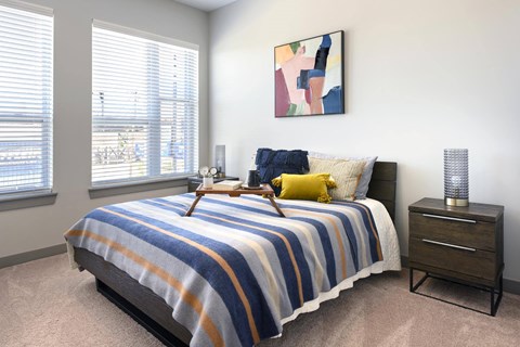 A bedroom with a bed, nightstand, and a painting on the wall.