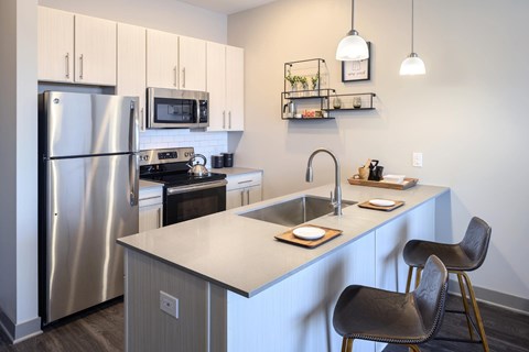 A modern kitchen with a stainless steel refrigerator and a black chair.