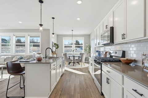 A modern kitchen with white cabinets and a wooden floor.