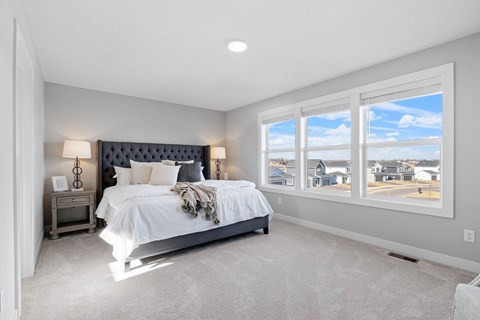 A bedroom with a large bed and a view of the outside through the window.