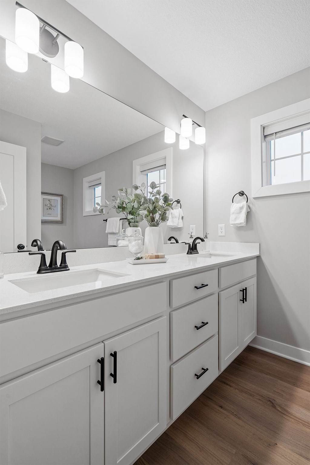A white bathroom with a double sink and a large mirror.