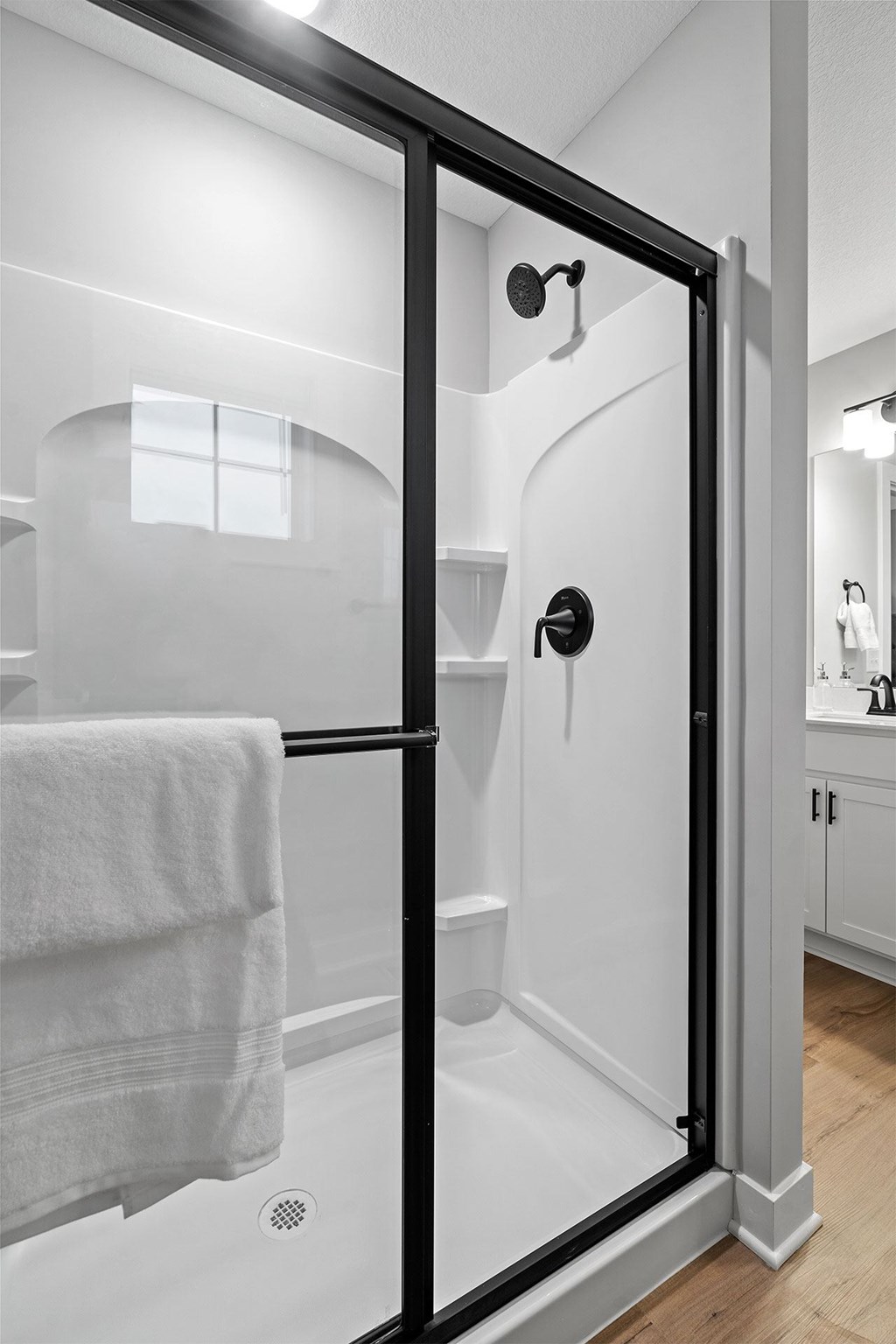 A white bathroom with a black shower door.