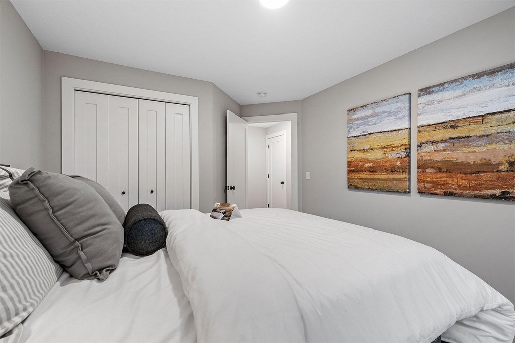 A bedroom with a large bed and a painting on the wall.