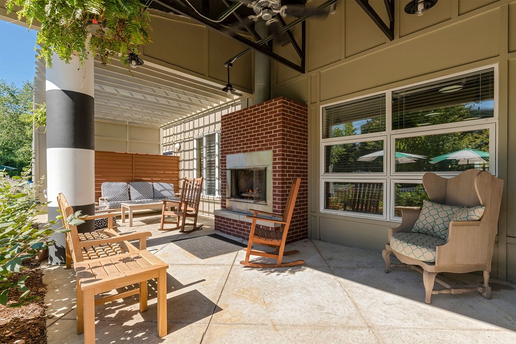 A sunny patio with a fireplace and chairs.