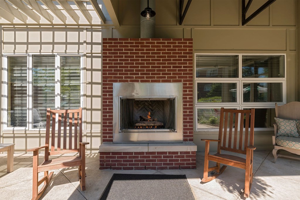 A fireplace with a brick surround and a wooden chair in front of it.