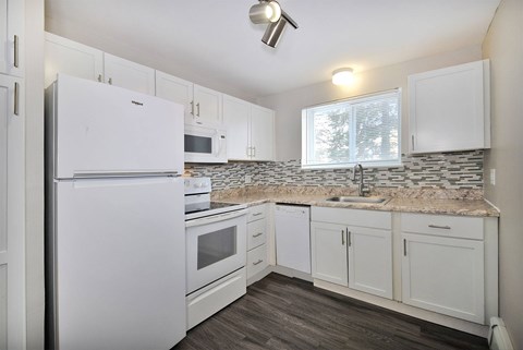 A kitchen with a white fridge and cabinets.