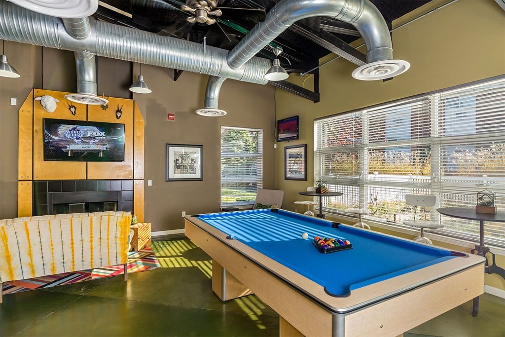 A pool table in a room with a television and a fireplace.