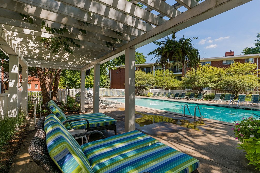 A pool area with sun loungers and a white pergola.