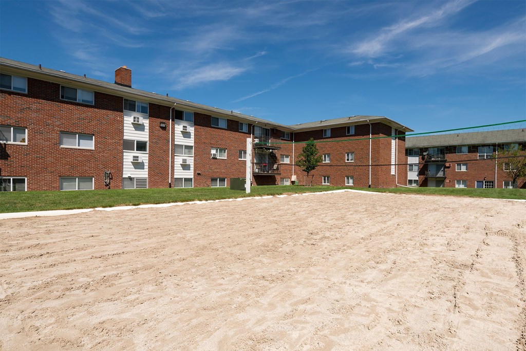 A large, empty parking lot in front of a multi-story brick building.