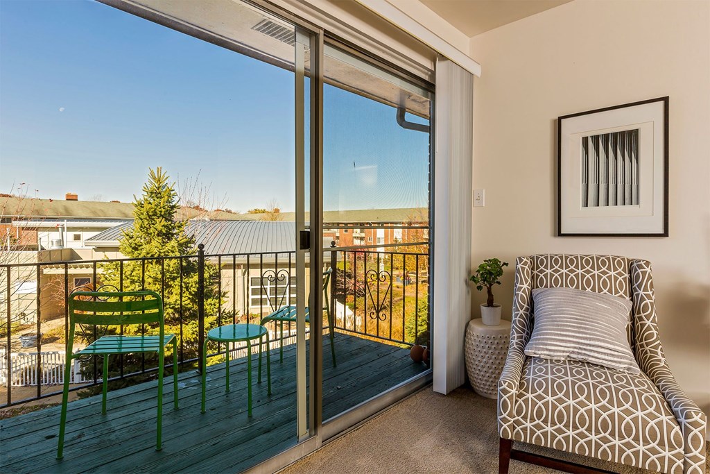 A balcony with a chair and a table is visible through a sliding glass door.