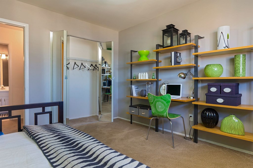 A room with a bed and a desk with a chair.