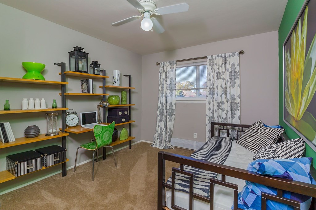 A room with a bed, a chair, and shelves with various items on them.