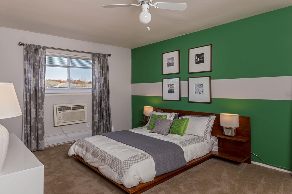 A bedroom with a bed, nightstands, and pictures on the wall.