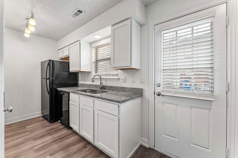 A kitchen with white cabinets and a black refrigerator.