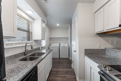 A kitchen with granite countertops and white cabinets.