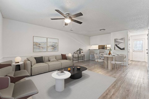 A living room with a grey couch, a white coffee table, and a ceiling fan.