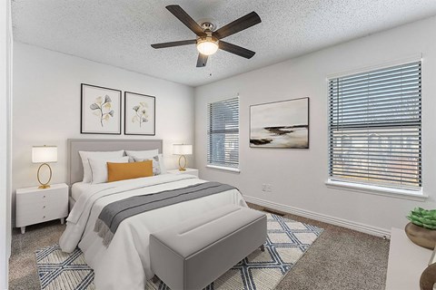 A bedroom with a bed, nightstands, and a ceiling fan.