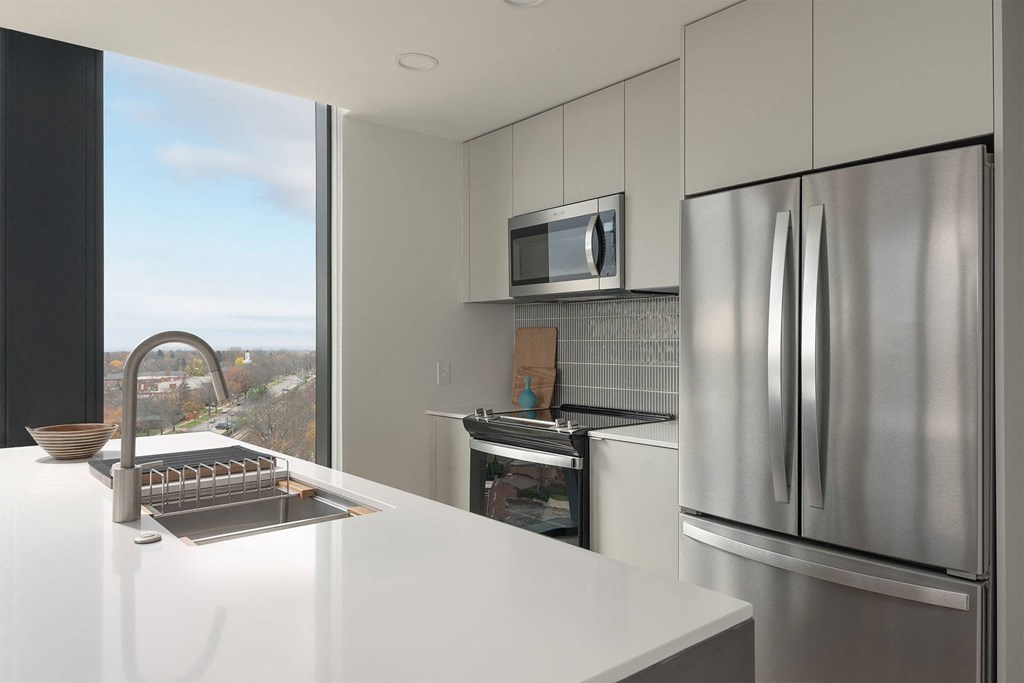 A modern kitchen with a stainless steel refrigerator and a white countertop.