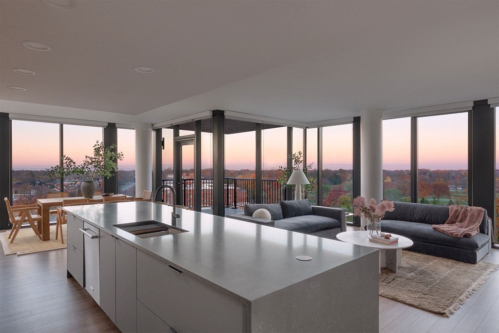 A modern kitchen with a large island and a view of the city at sunset.