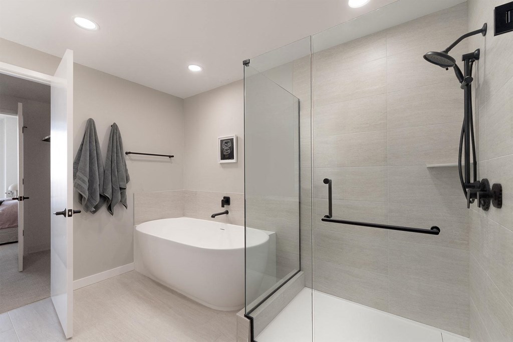 A modern bathroom with a white tub and a walk-in shower.