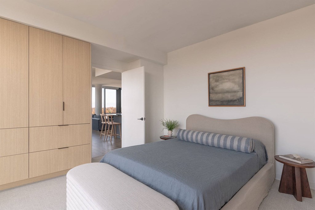 A bedroom with a bed, a small table, and a painting on the wall.