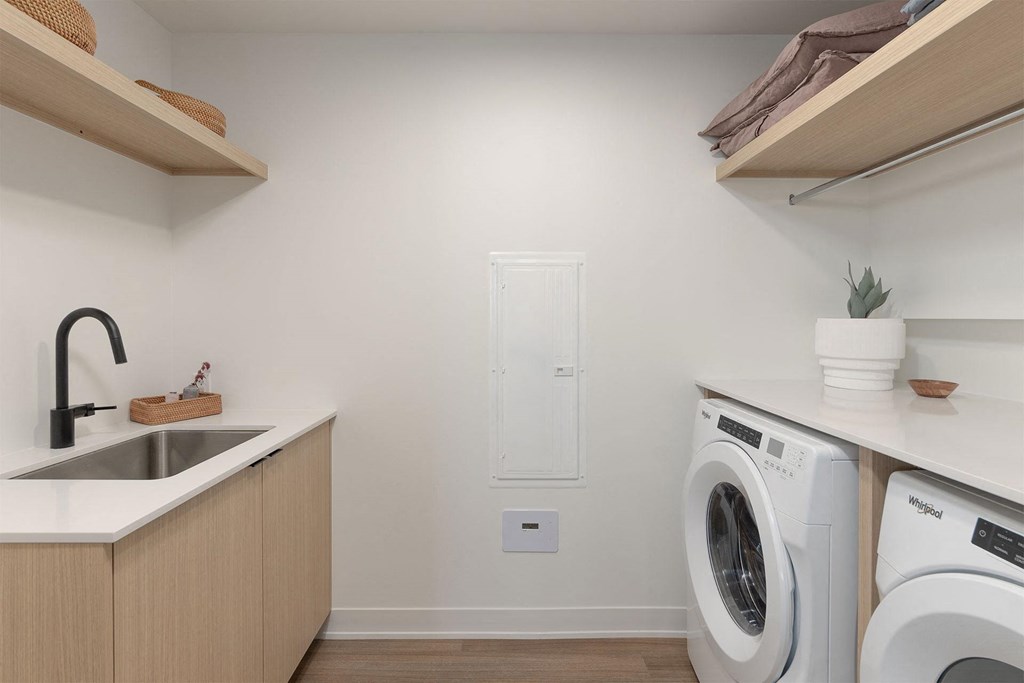 A small laundry room with a sink and two washing machines.