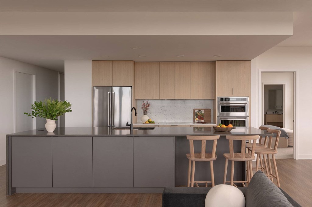 A modern kitchen with a grey countertop and wooden cabinets.