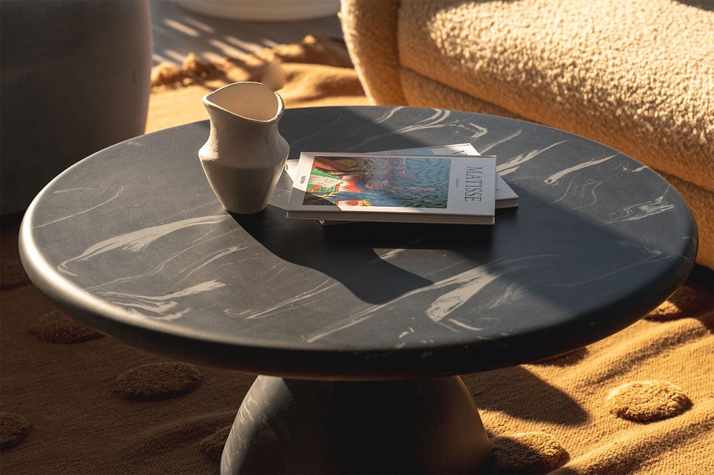 A round table with a book and a cup on it.