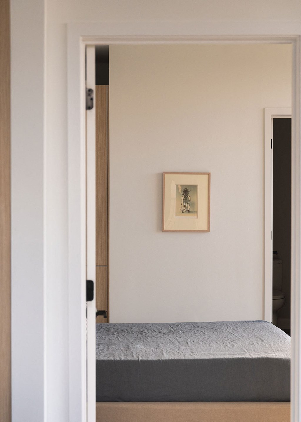 A bedroom with a bed and a picture on the wall.