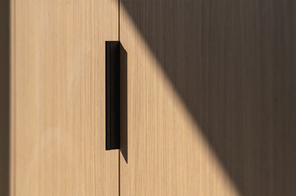A black handle on a wooden door.
