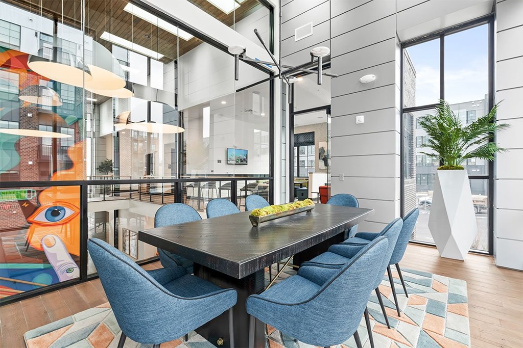 A modern dining room with a glass table and blue chairs.