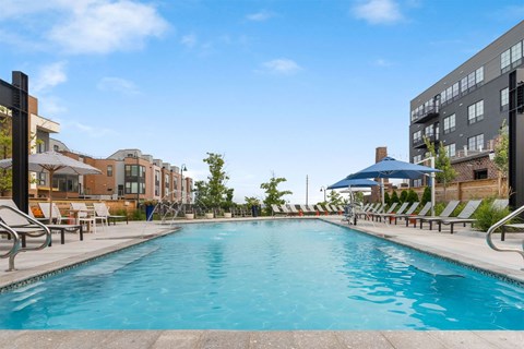 A large outdoor swimming pool surrounded by sun loungers and umbrellas.
