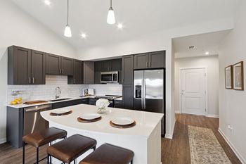 A kitchen with a white island and brown stools.