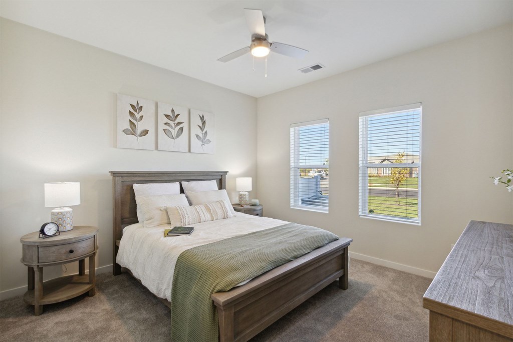 A bedroom with a bed, nightstand, and a fan.