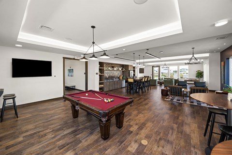 A room with a pool table and a bar area.